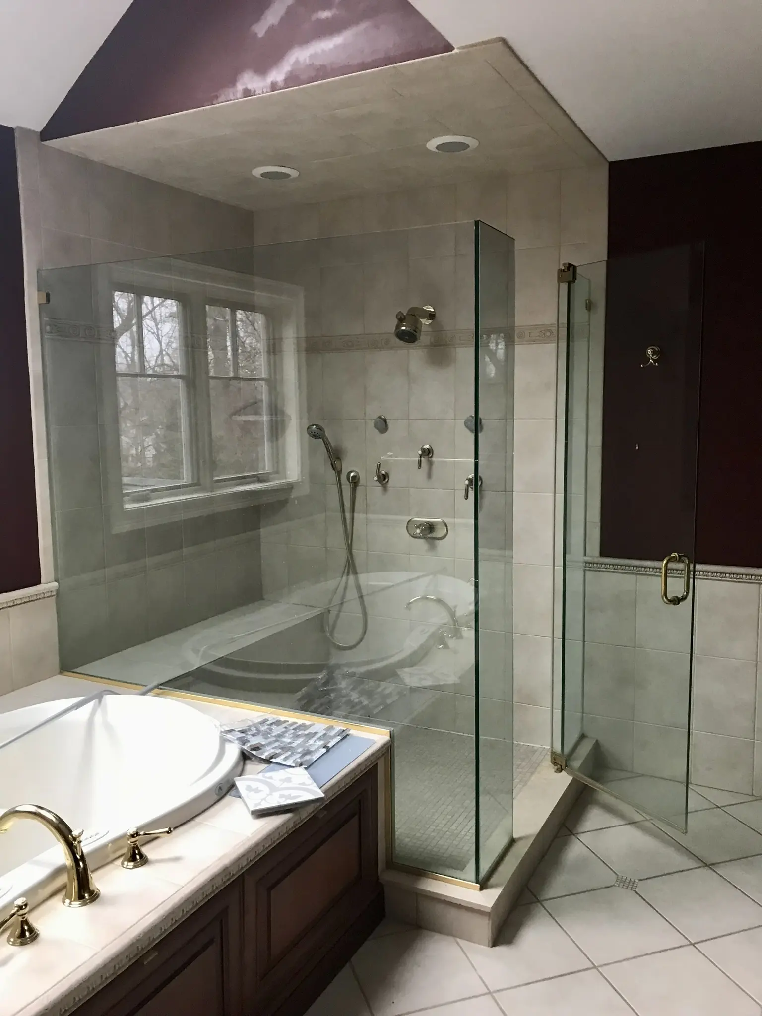 Bright bathroom with marble tile, glass shower, and tub.