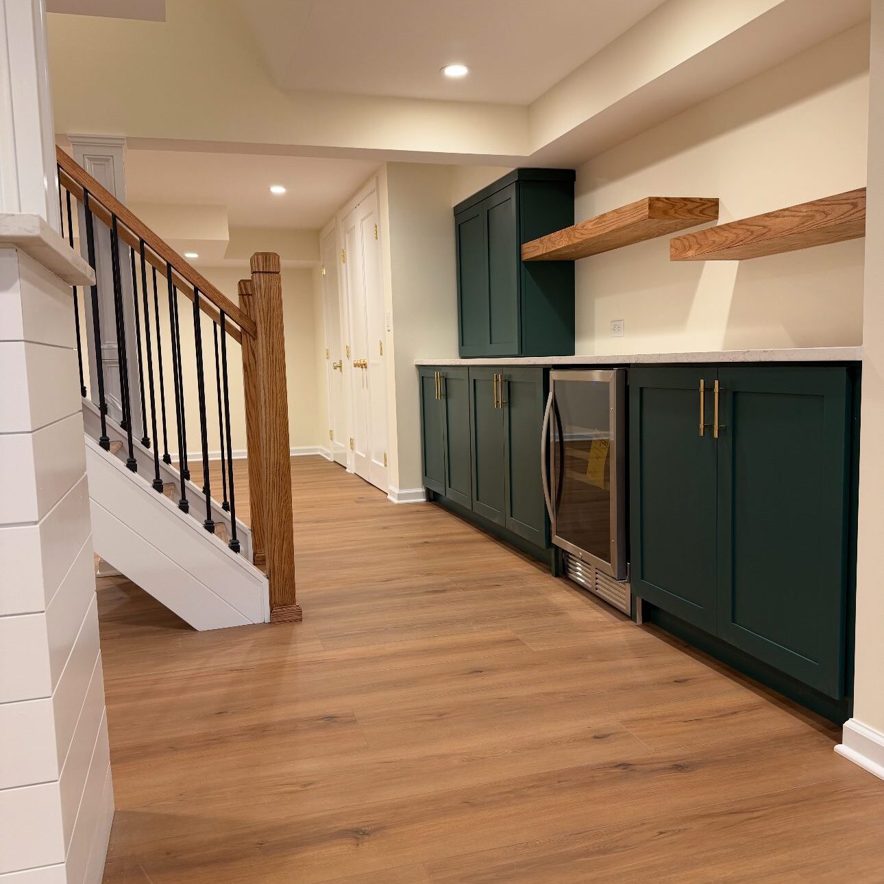 Basement kitchenette with green cabinets and wine fridge